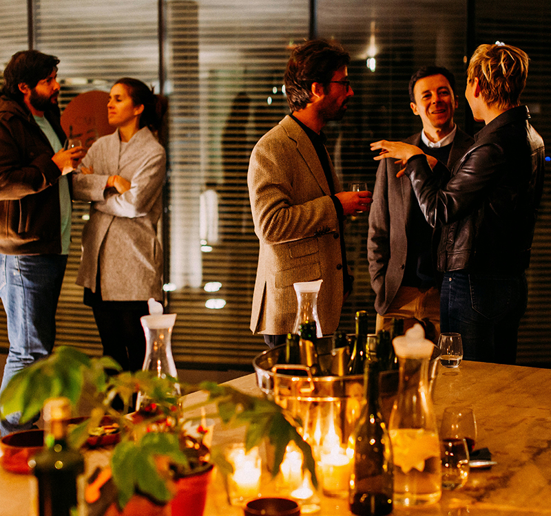 a group of people standing around a table with bottles and glasses