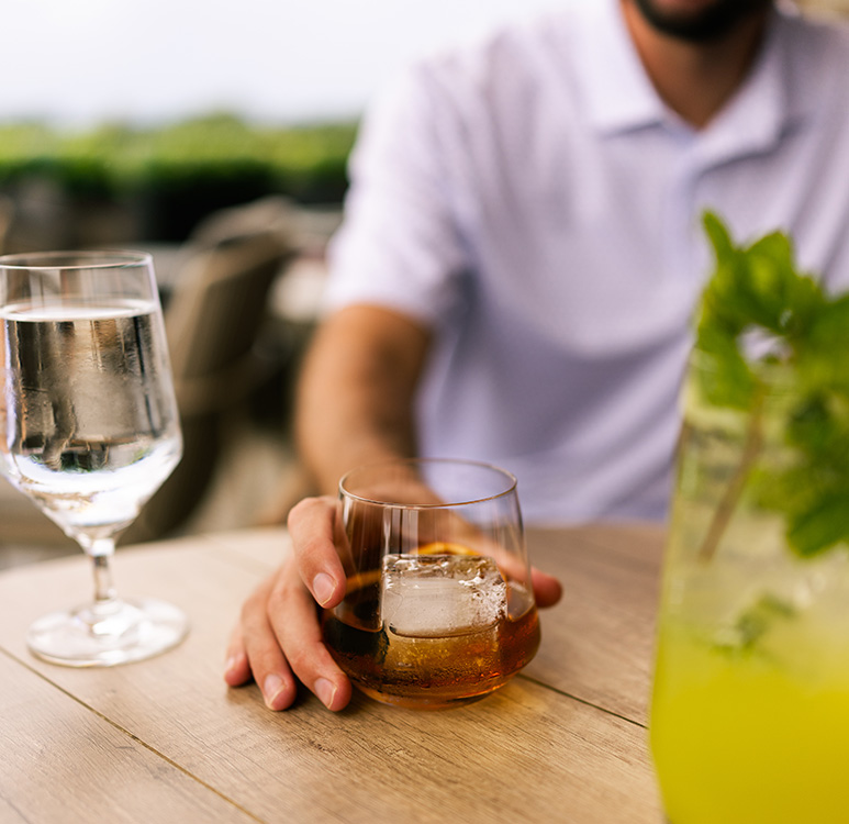 a hand holding a glass of ice cube and a glass of water