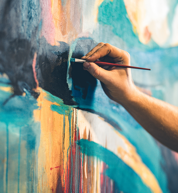 a hand holding a brush painting a painting on a wall