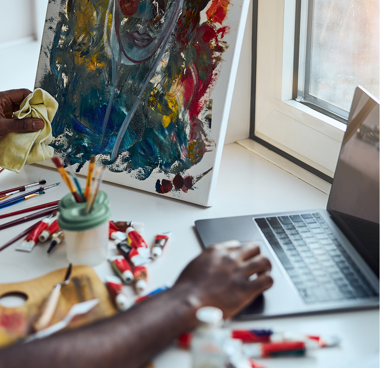a person using a laptop to paint on a painting