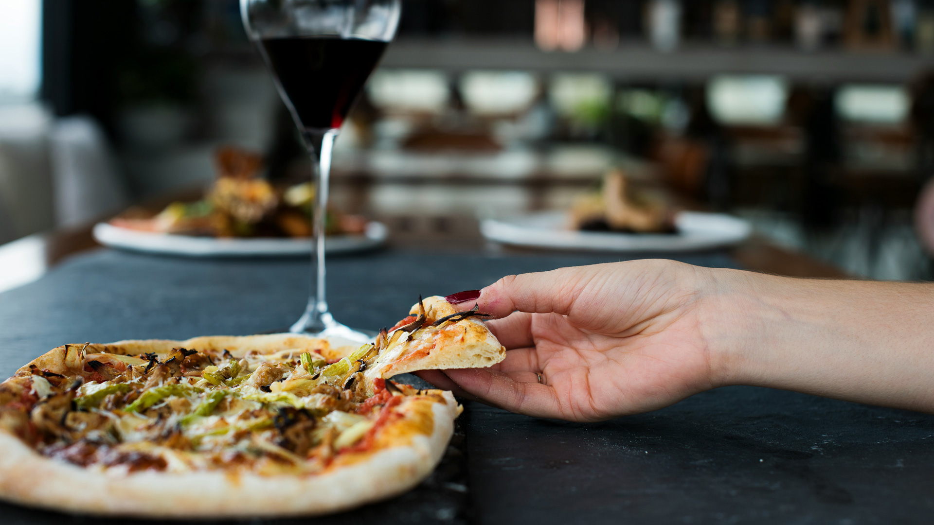a hand holding a slice of pizza