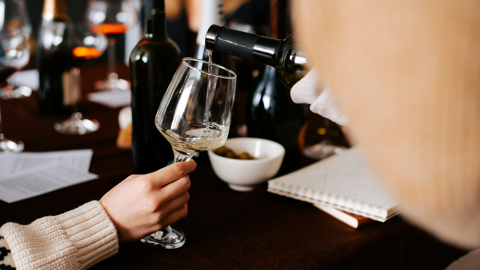 a person pouring wine into a glass