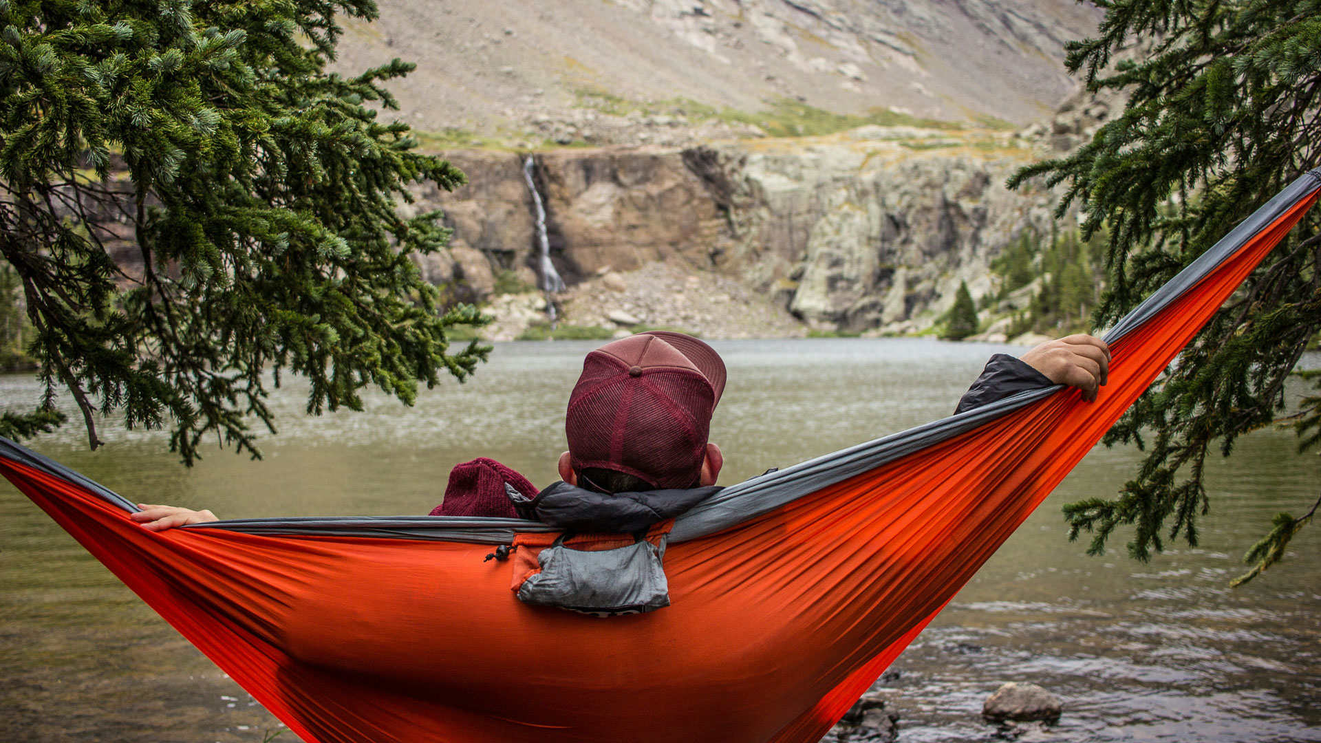 a person in a hammock overlooking a body of water
