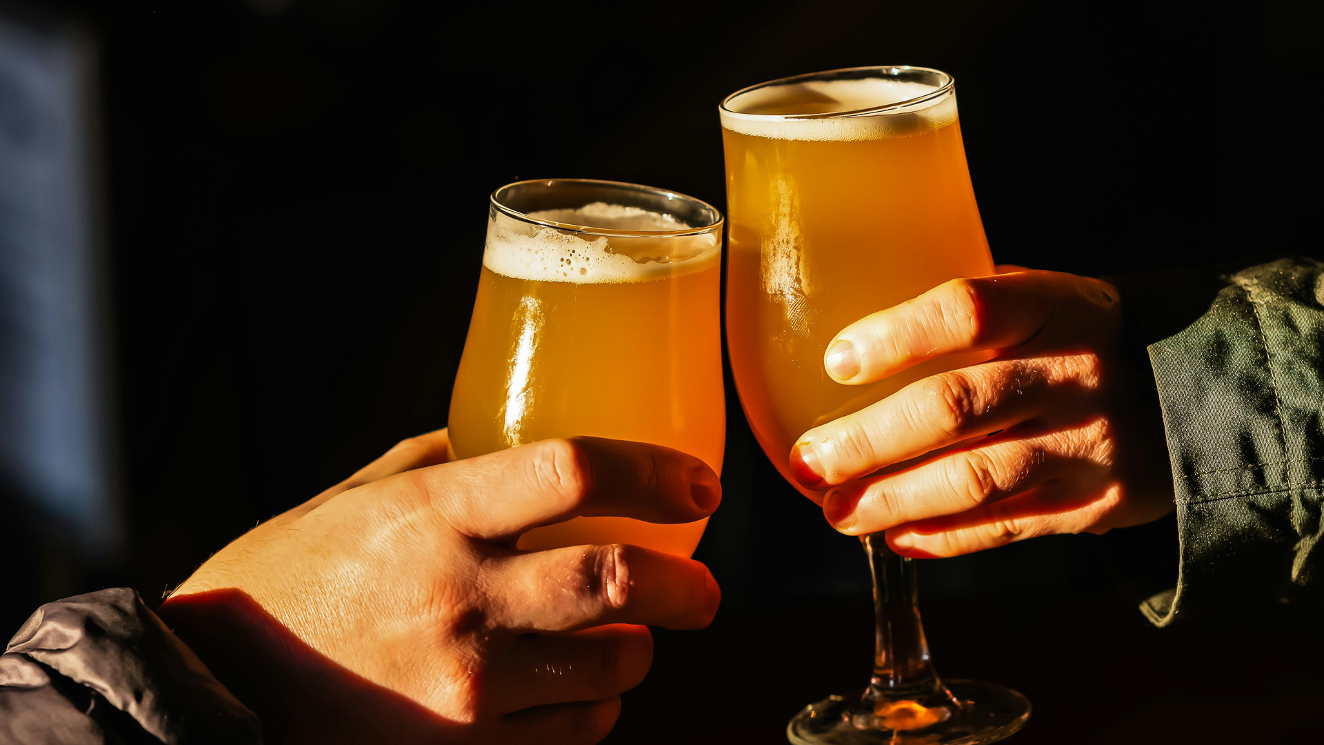 a pair of hands holding glasses of beer