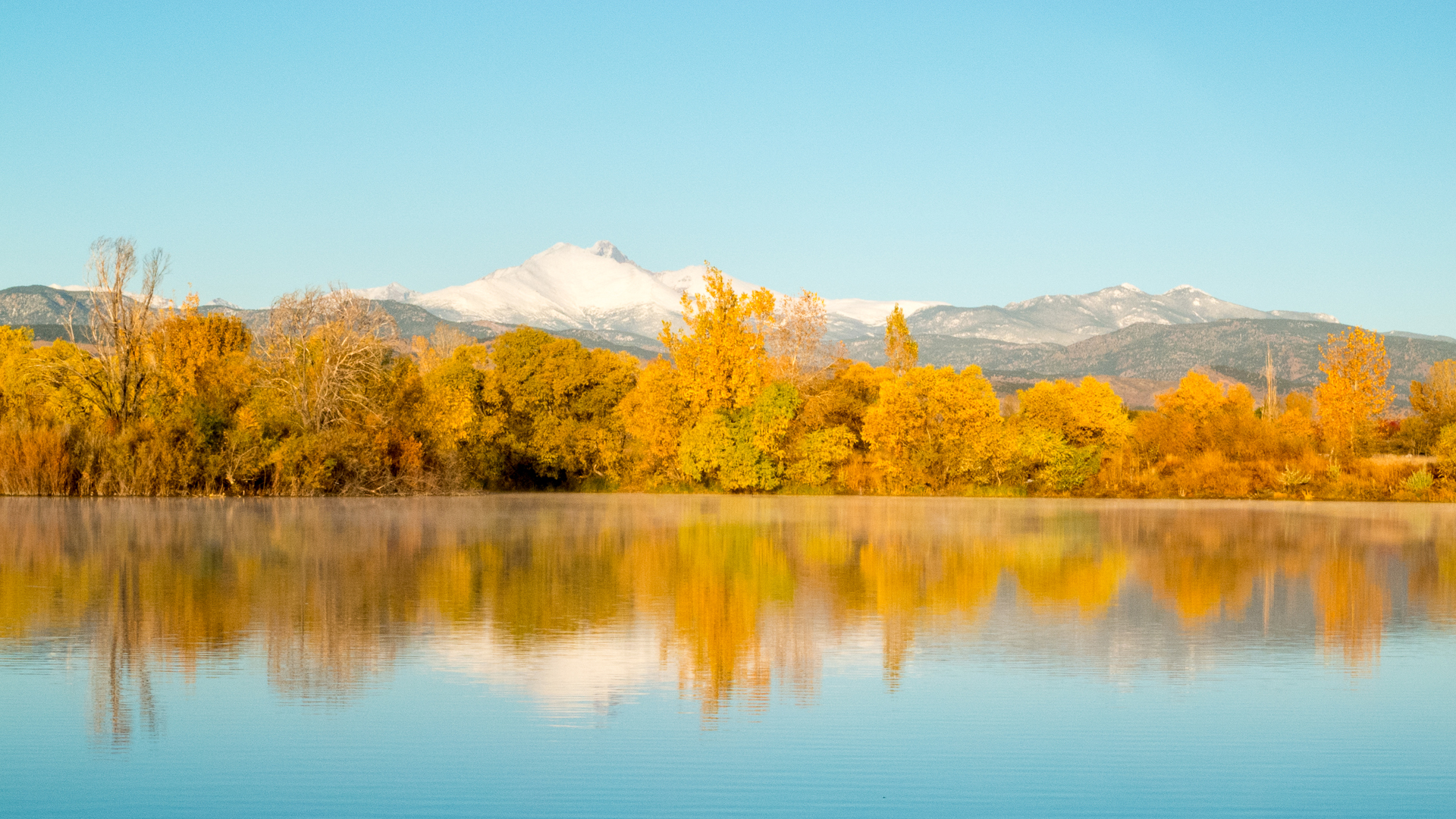 a lake with trees and mountains in the background
