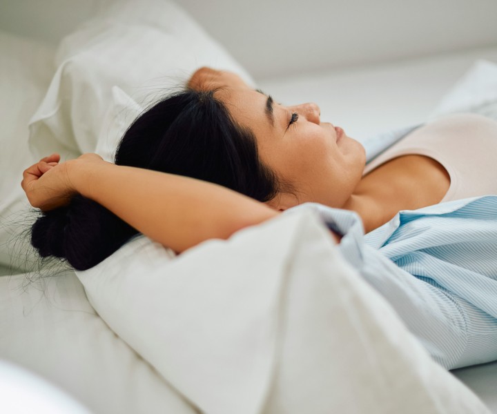 a woman lying in bed with her hands behind her head