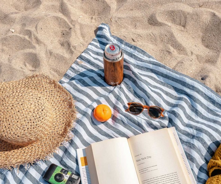 a blanket with a book and sunglasses on it