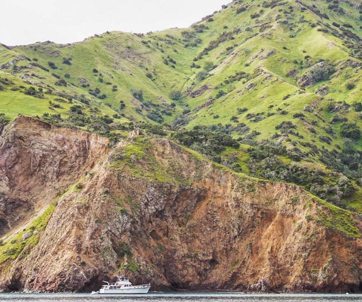 a boat on the water near a cliff