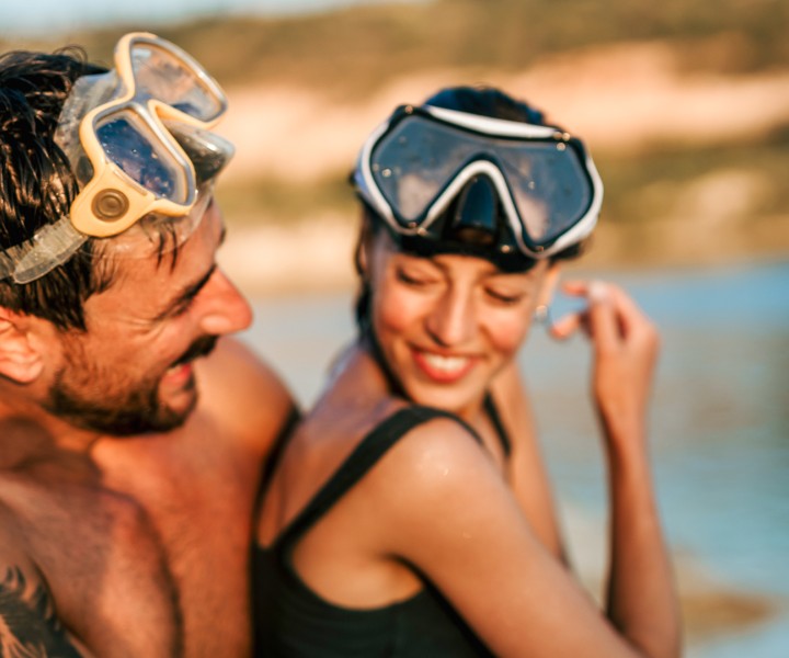 a man and woman wearing goggles and standing in the water