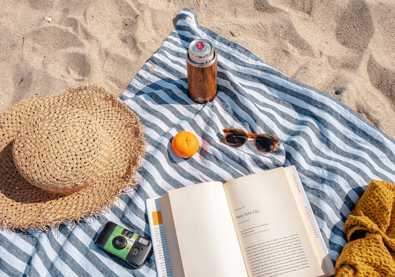 a blanket with a book and sunglasses on it