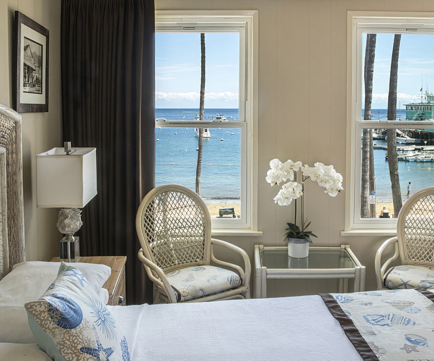 a bedroom with a bed and chairs and a window overlooking the ocean