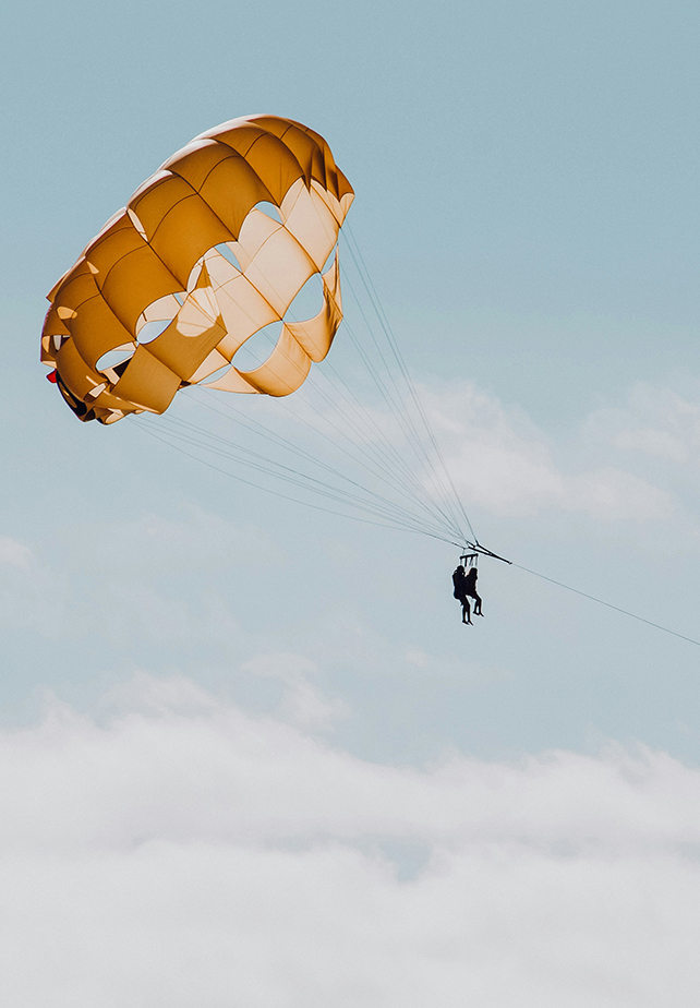 a couple of people flying on a parachute