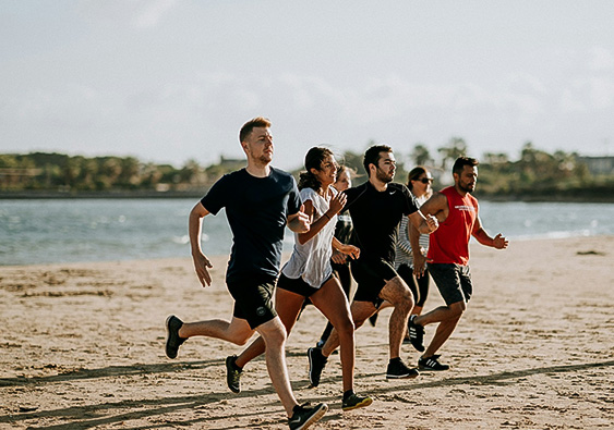 a group of people running on a beach