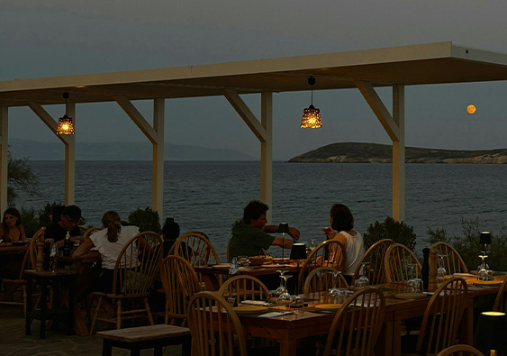 a group of people sitting at tables by the water