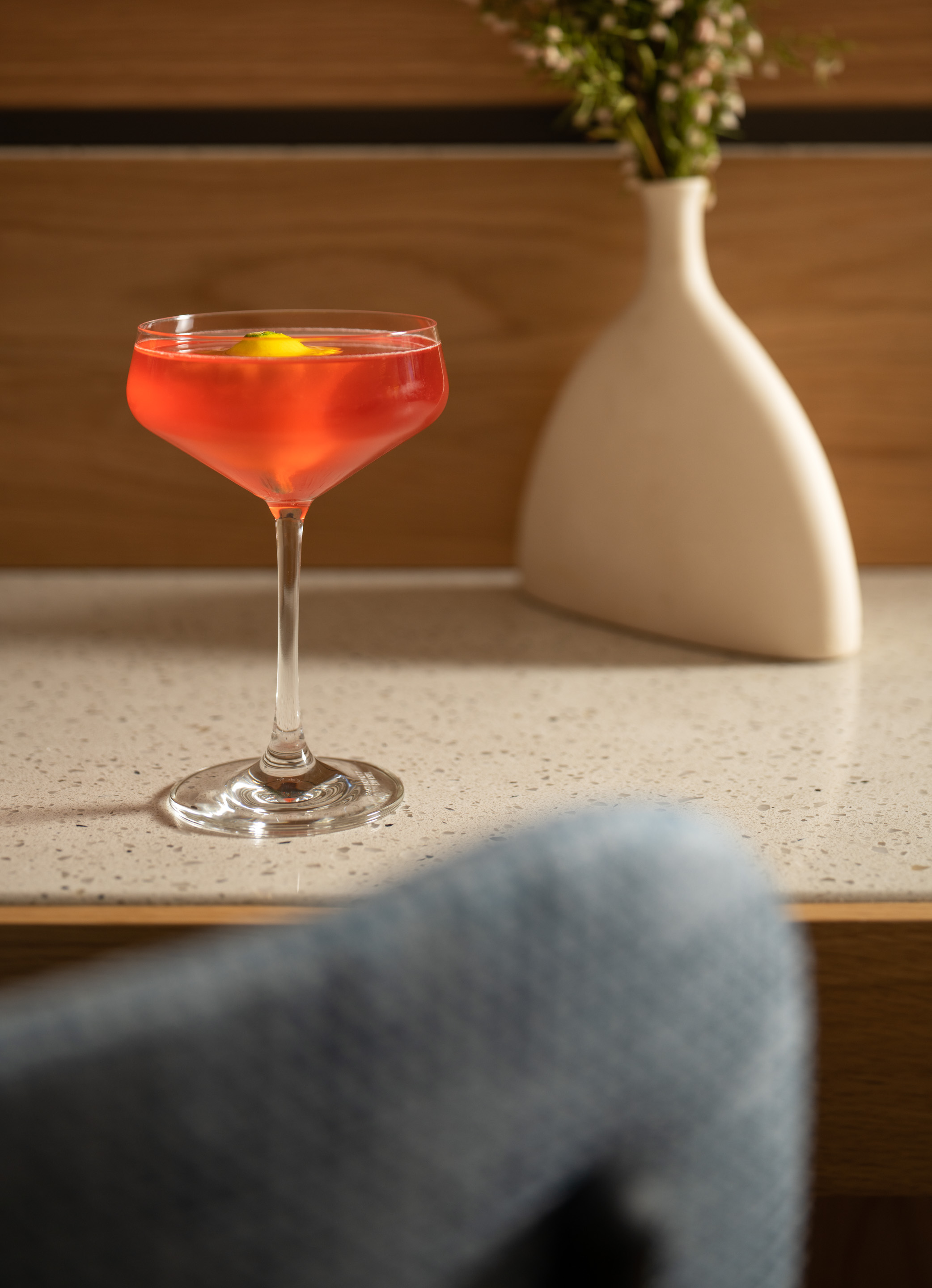 a glass of red liquid with a lemon in it