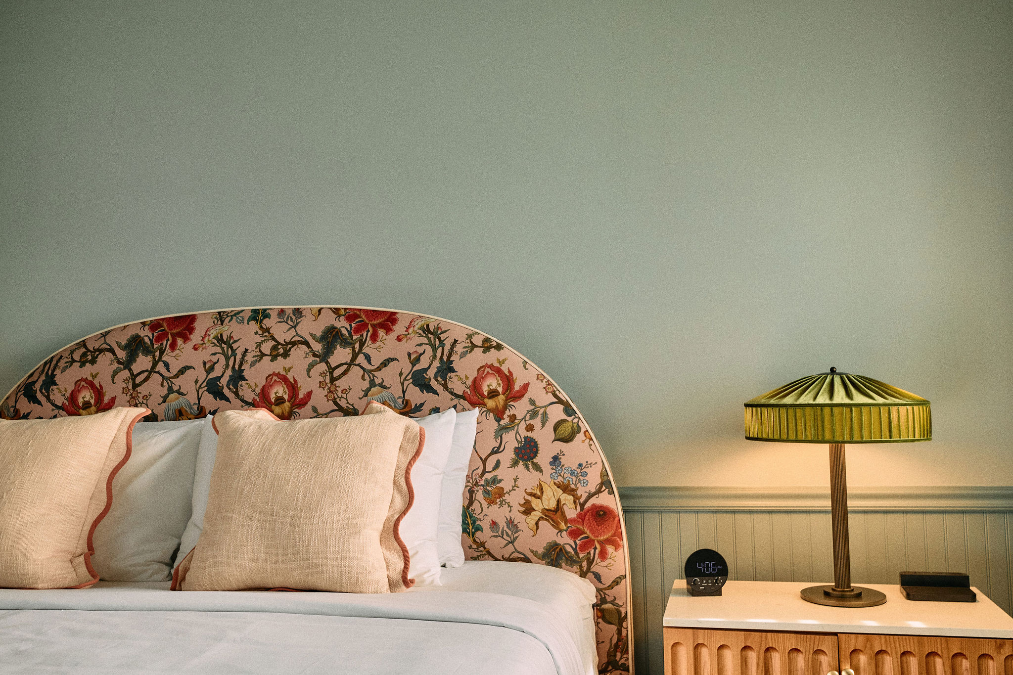 a bed with a floral headboard and a lamp