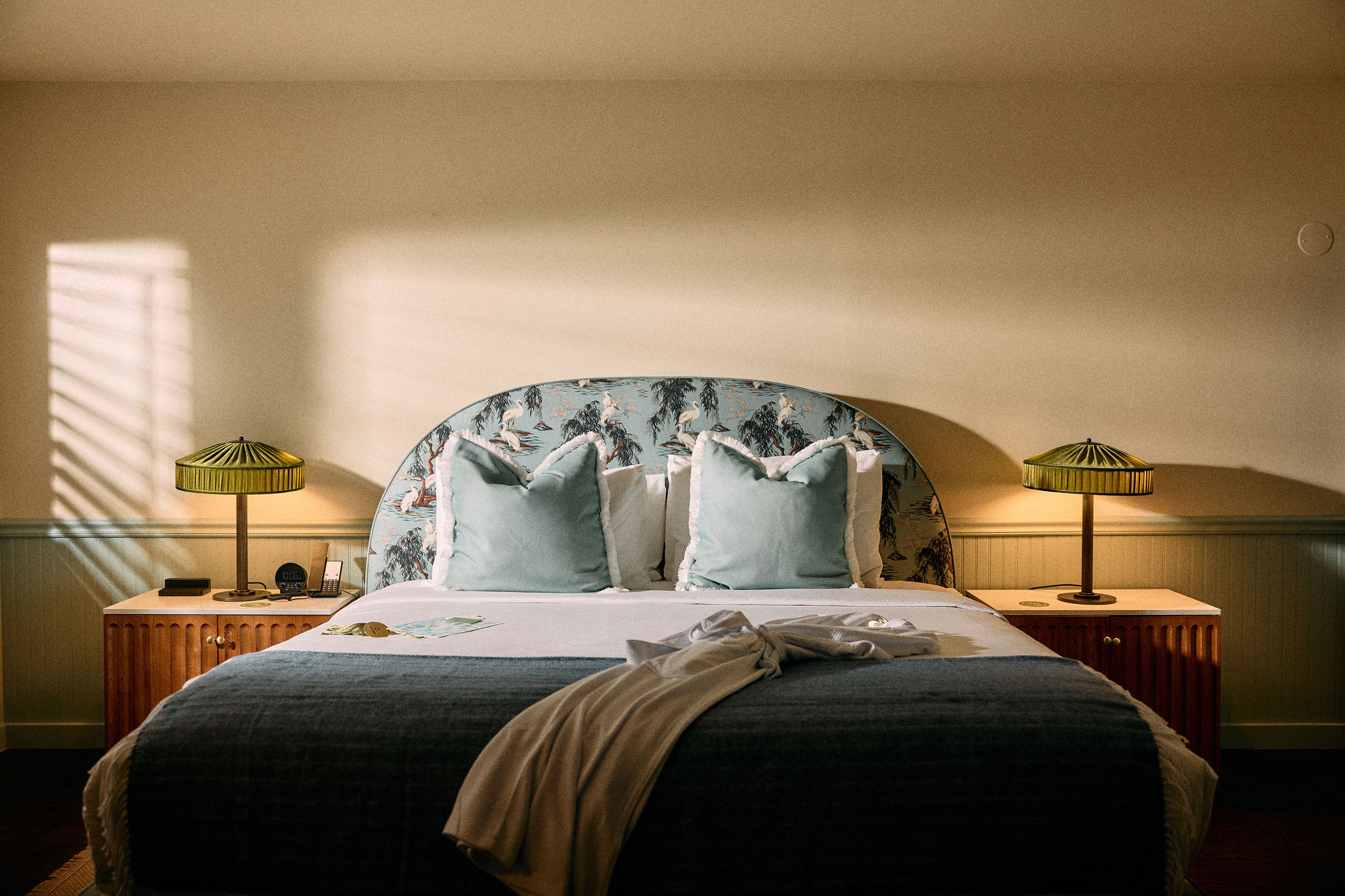 a bed with a blue headboard and two lamps