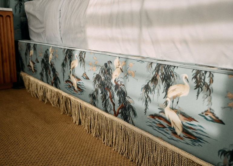 a bed with a wallpaper and fringe