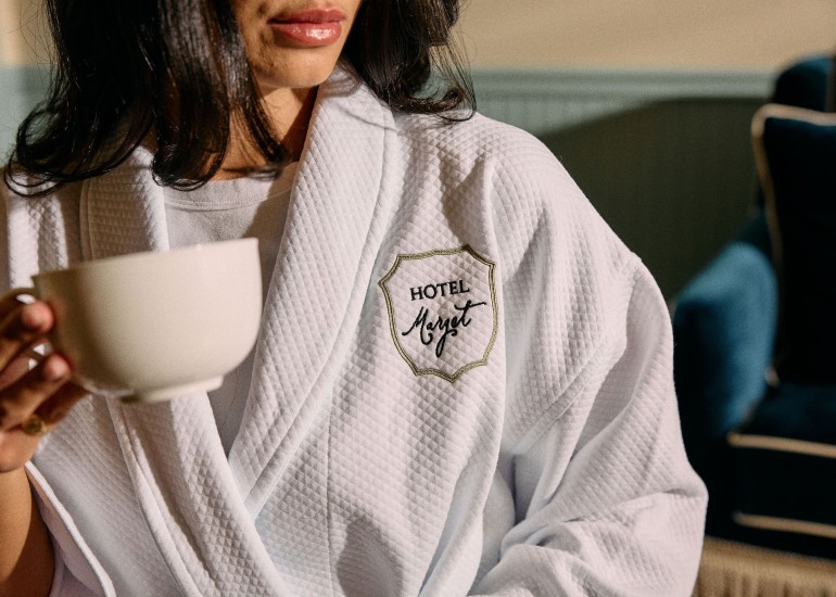 a woman wearing a white robe holding a cup