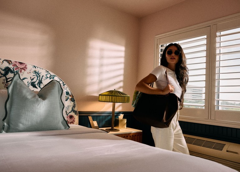 a woman in a room with a bed and a lamp