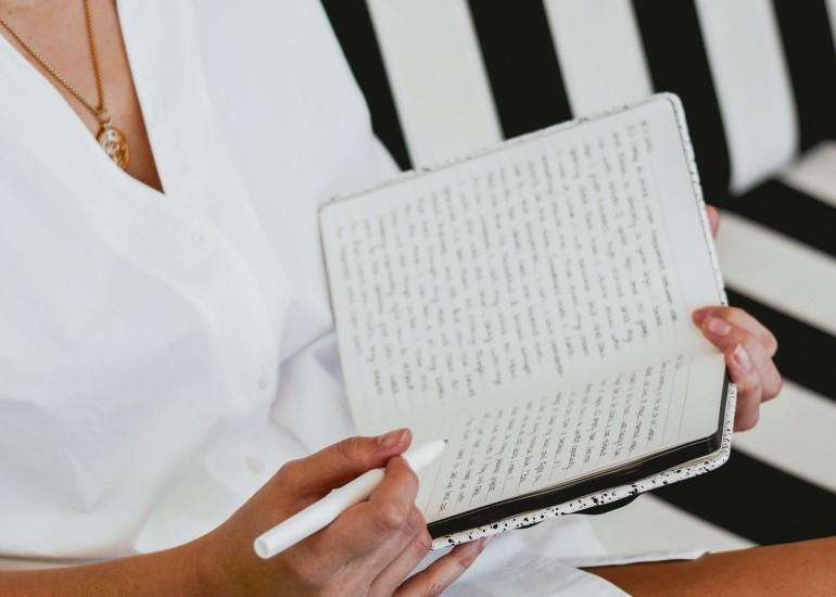 a person holding a pen and a notebook