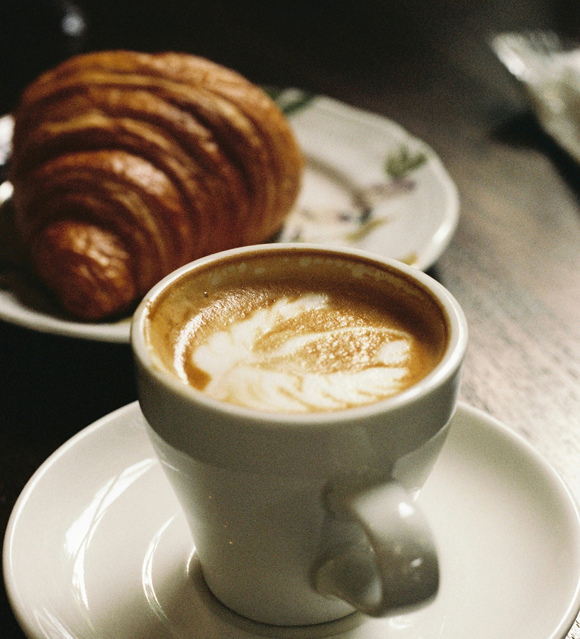 a cup of coffee and a croissant on a plate