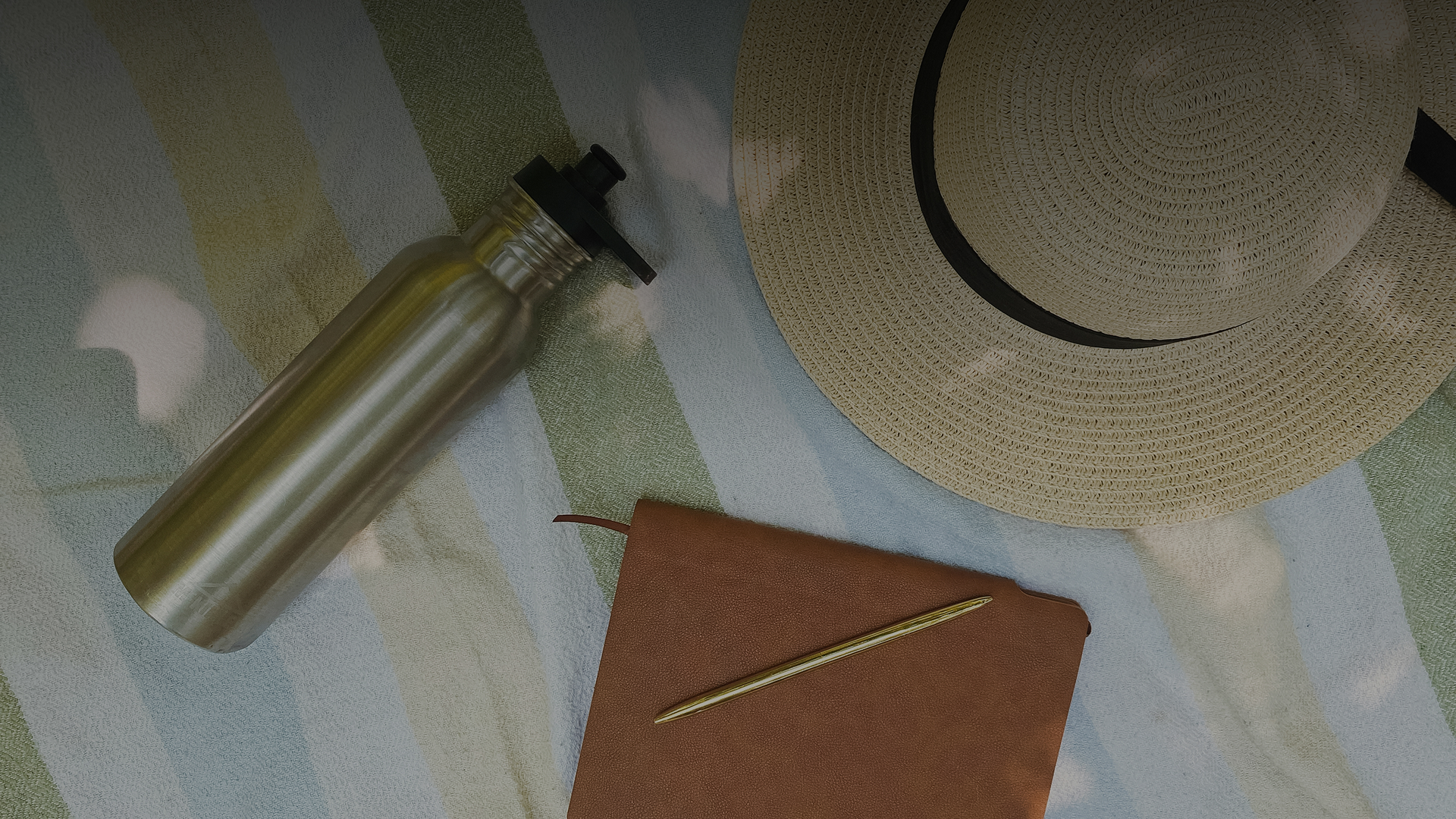 a straw hat and a water bottle on a blanket