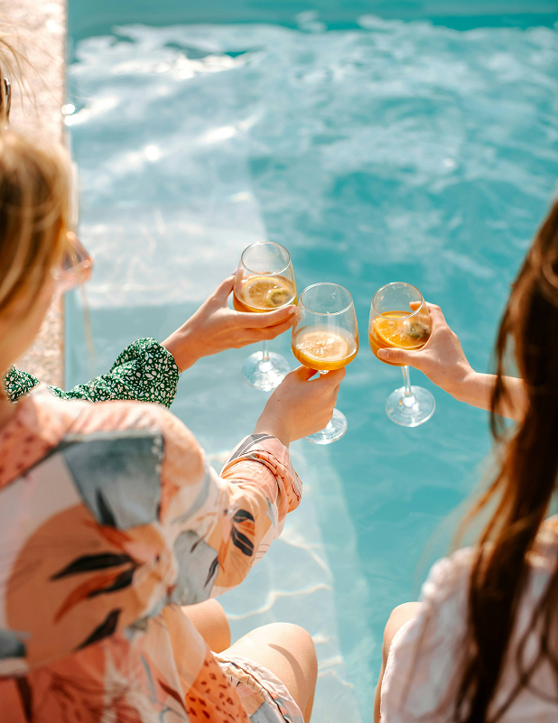 a group of women holding wine glasses by a pool