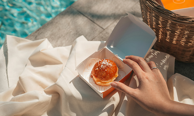 a hand holding a pastry in a box