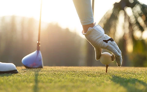 hand placing golf ball on tee
