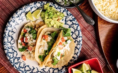 a plate of tacos with guacamole and lime