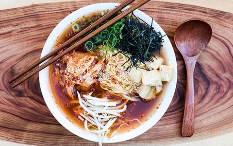 a bowl of noodle soup with chopsticks and a spoon