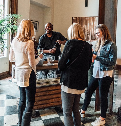 three women in front of  mixologist making drinks