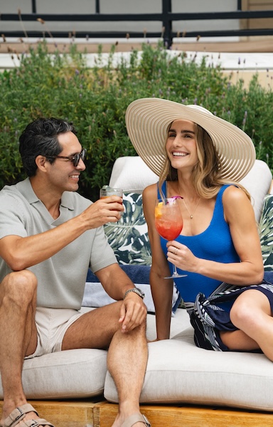 a man and woman sitting on a couch with drinks