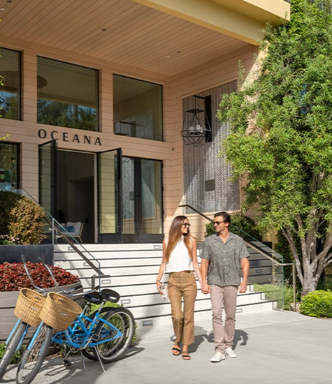 a man and woman holding hands and walking in front of a building