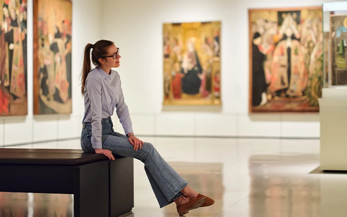 a woman sitting on a bench in a museum
