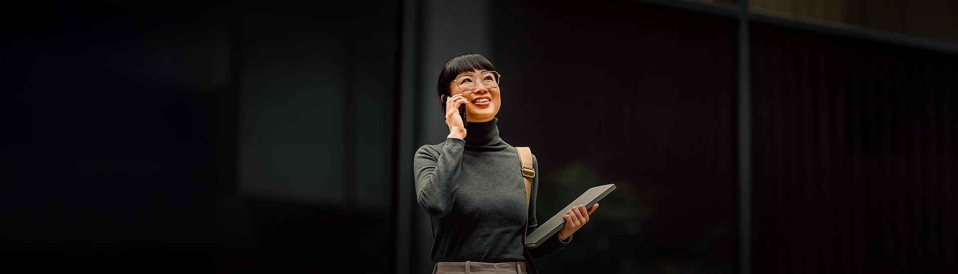 a woman holding a laptop and talking on a cell phone