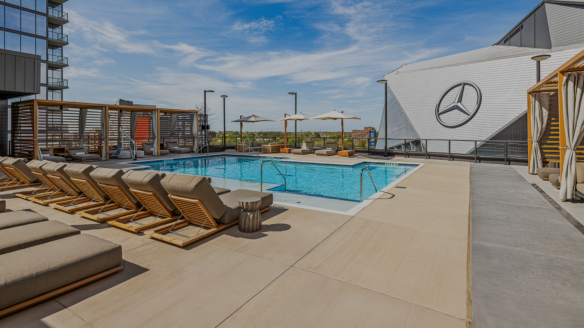 a pool with chairs and umbrellas on a rooftop