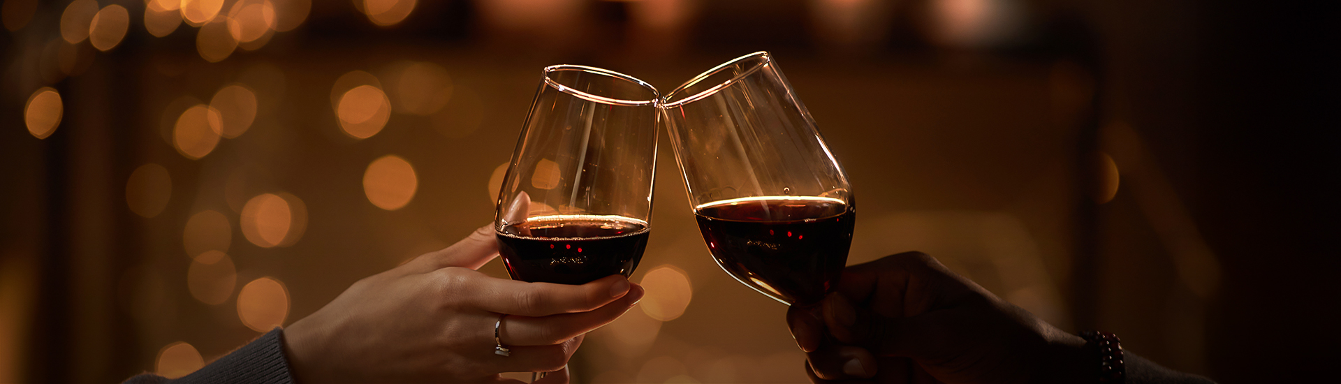 a pair of hands clinking wine glasses