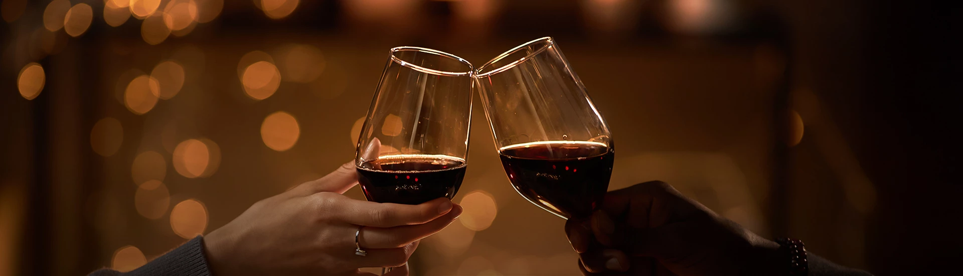 a pair of hands clinking wine glasses