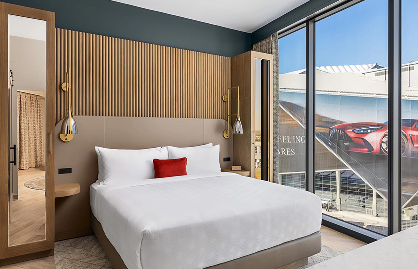 a bed with a red pillow and a lamp next to a window