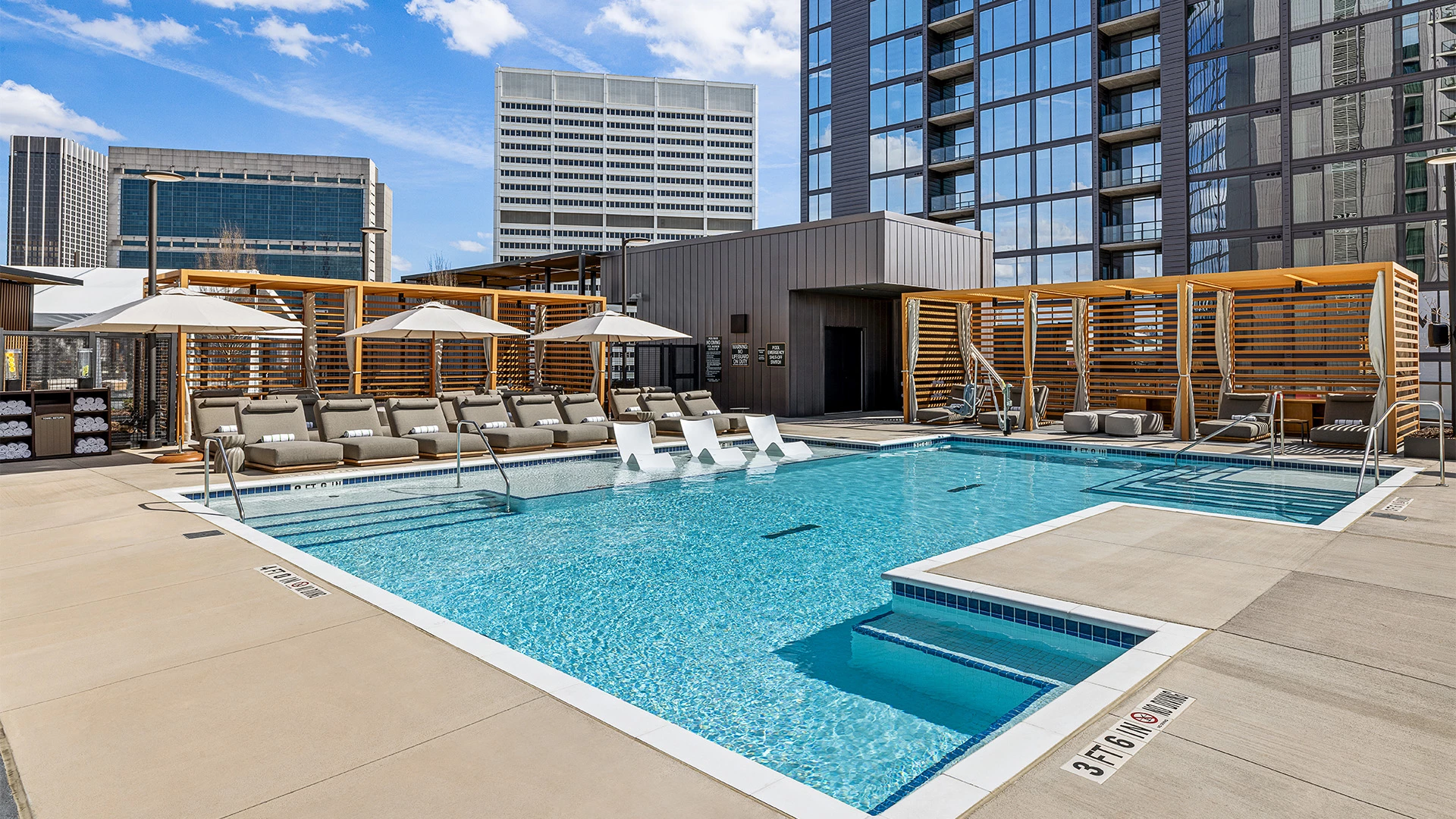 a pool with chairs and umbrellas in front of a building