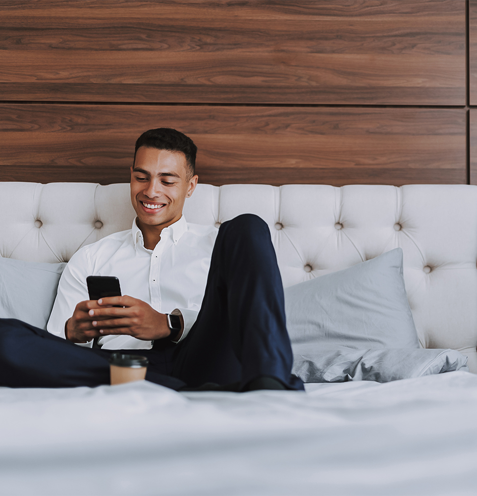 a man sitting on a bed looking at a phone