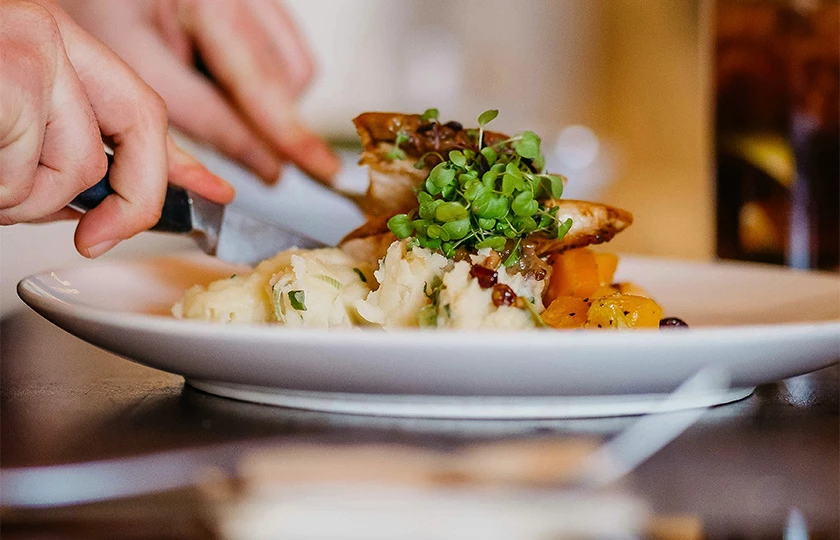 a person cutting food on a plate