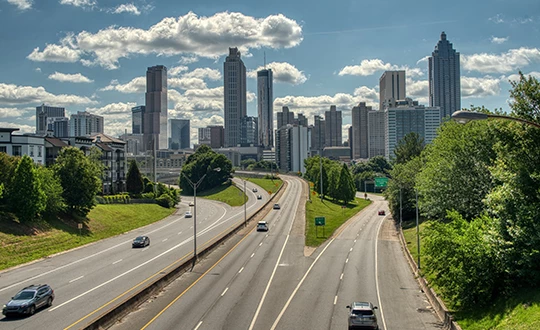 a highway with cars on it and a city skyline in the background
