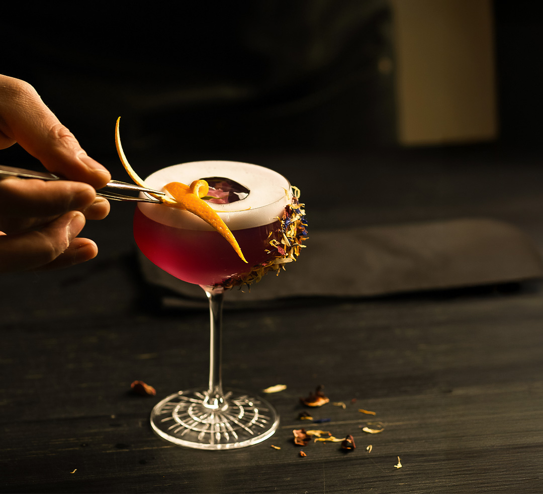 a person holding tweezers to a drink