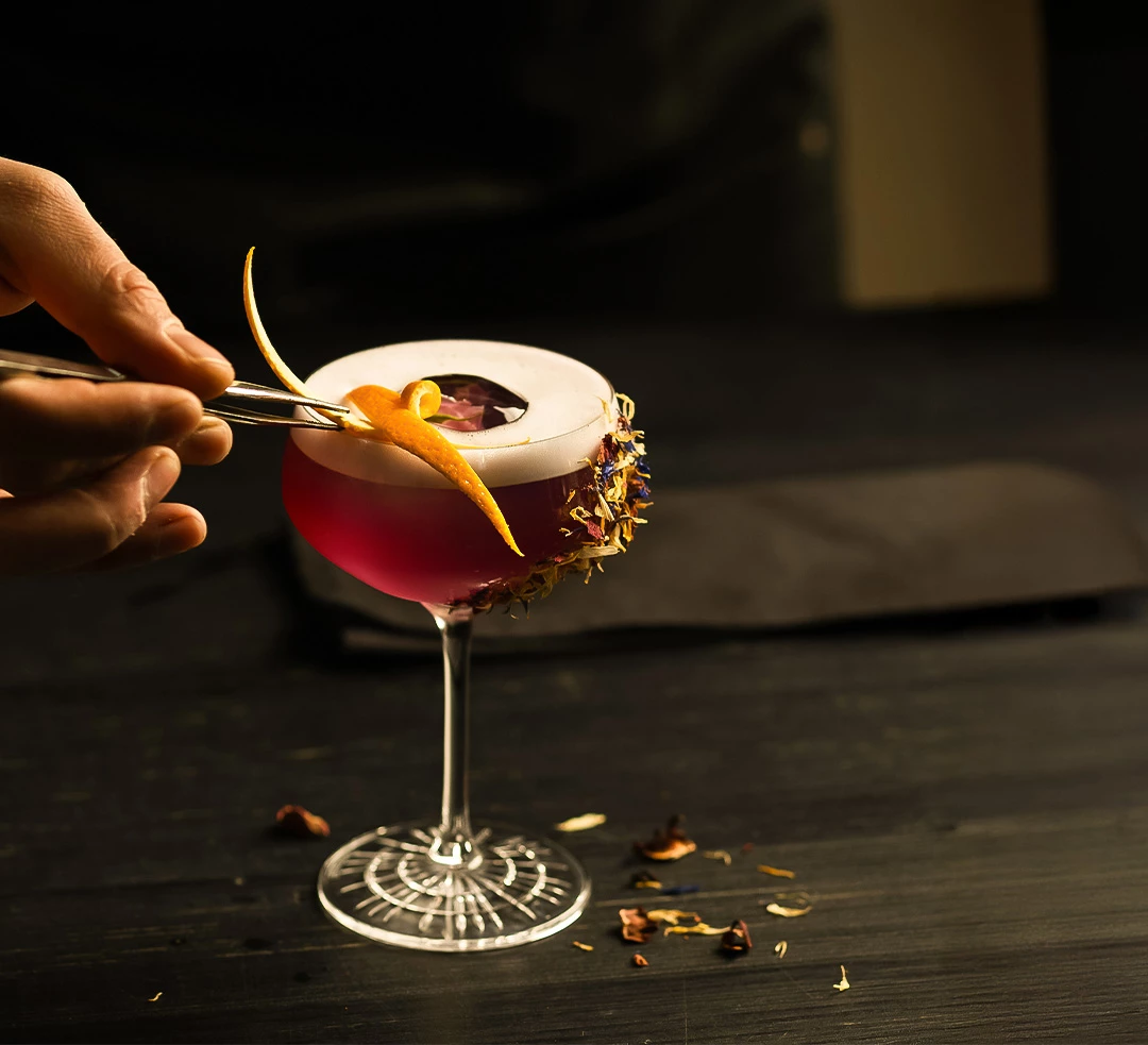 a person holding tweezers to a drink