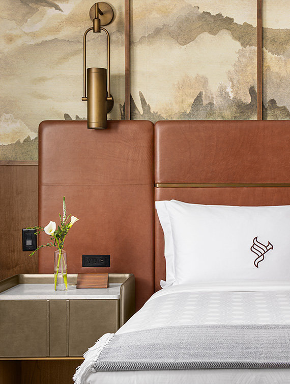 a bed with a white pillow and a vase of flowers on a table
