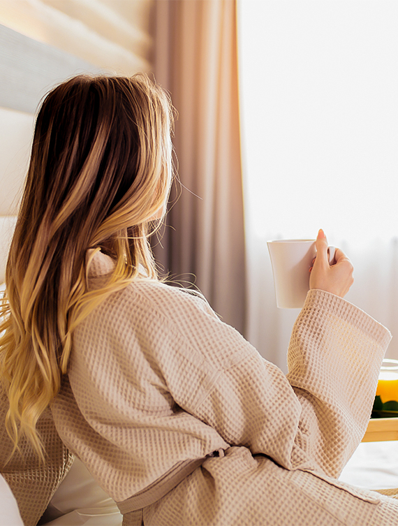 a woman in a bathrobe holding a cup