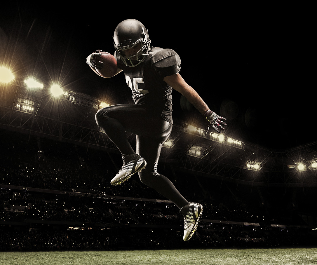 a football player in a black uniform jumping with a ball